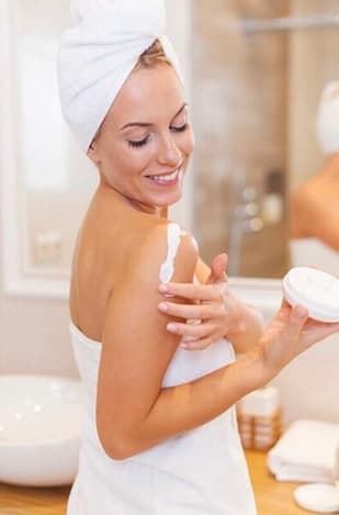 Smiling woman enjoying her application of organic body lotion