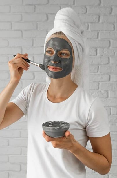 Woman applying activated charcoal as her natural skin detox method