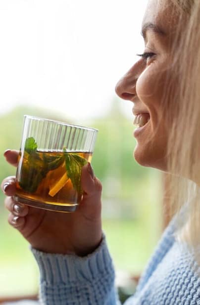 Smiling woman drinking herbal tea as her skin detox method