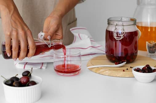 A person pouring a fermented beverage in a glass
