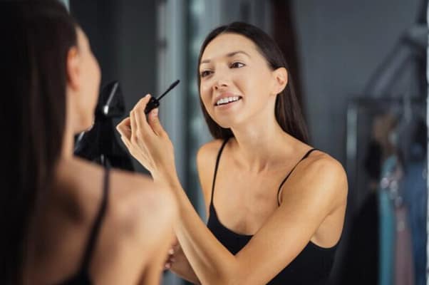 Woman applying essential makeup on a big mirror