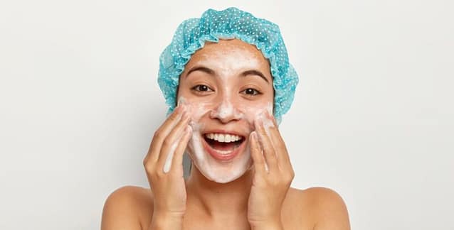Smiling woman enjoying washing her face with natural foaming cleanser