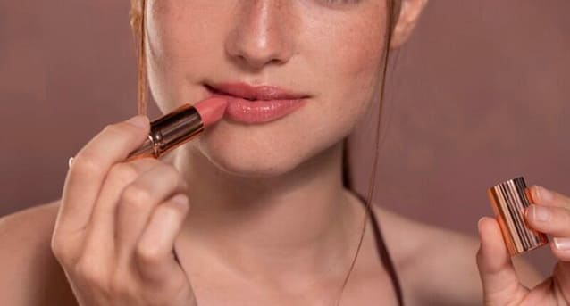 Woman applying lipstick while facing the camera