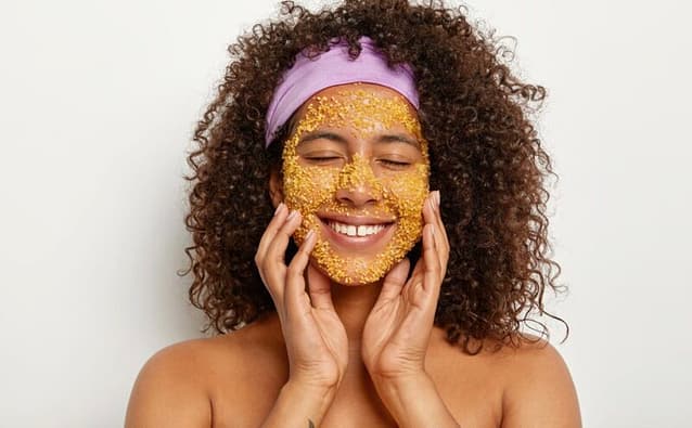 Smilling woman with turmeric face mask on her face