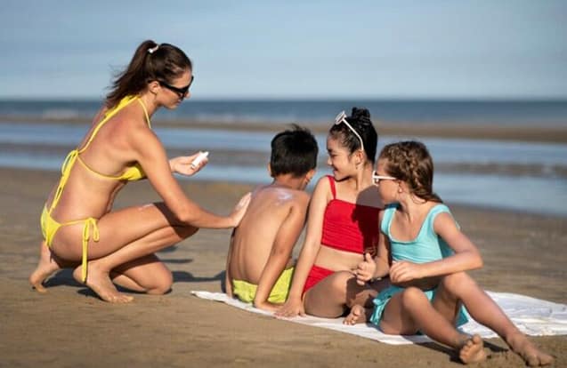 A mom making sure her kids reapply sunscreen