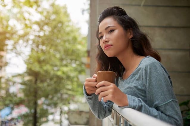 A woman on her balcony enjoying her tea and nature.