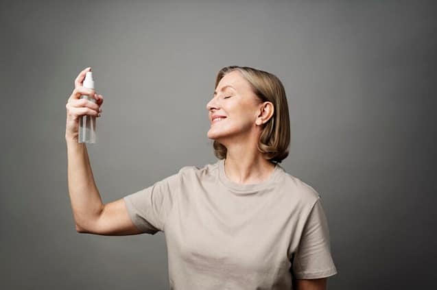 96D7C409-F5AD-43AF-8E58-81D7C663E9C9 Smiling woman applying a coconut water face mist