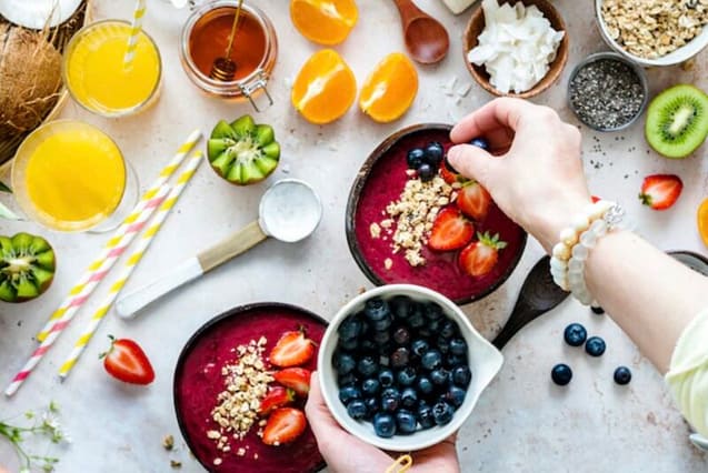 A lady doing some fruit toppings on her Smoothie Bowl 