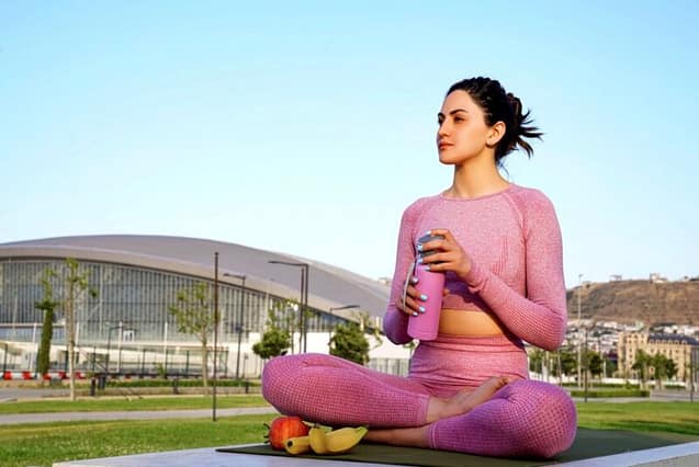 Woman relaxing and drinking tea at the park after doing some exercises 