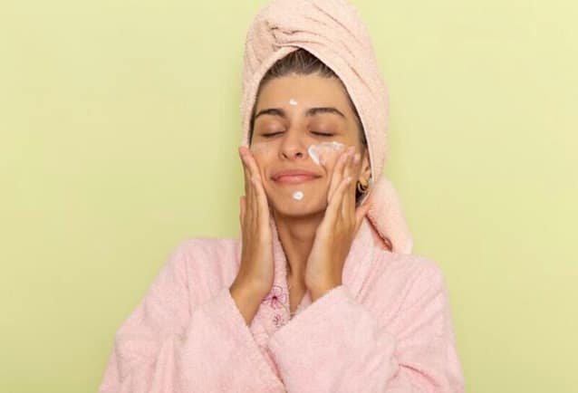 Woman applying face moisturizer