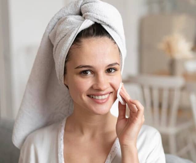 Woman smiling while applying skin toner