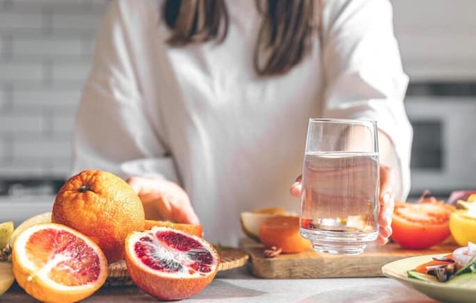 Woman with hydrating food and beverage on her table