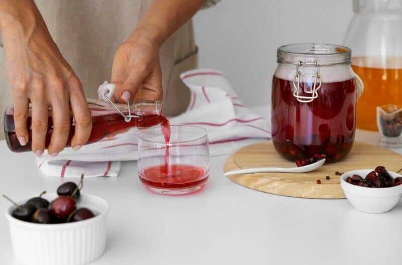 A person pouring a fermented beverage in a glass