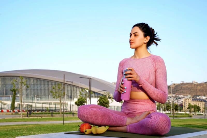 Woman relaxing and drinking tea at the park after doing some exercises 