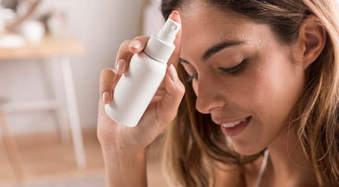 Woman holding close to her face a setting spray